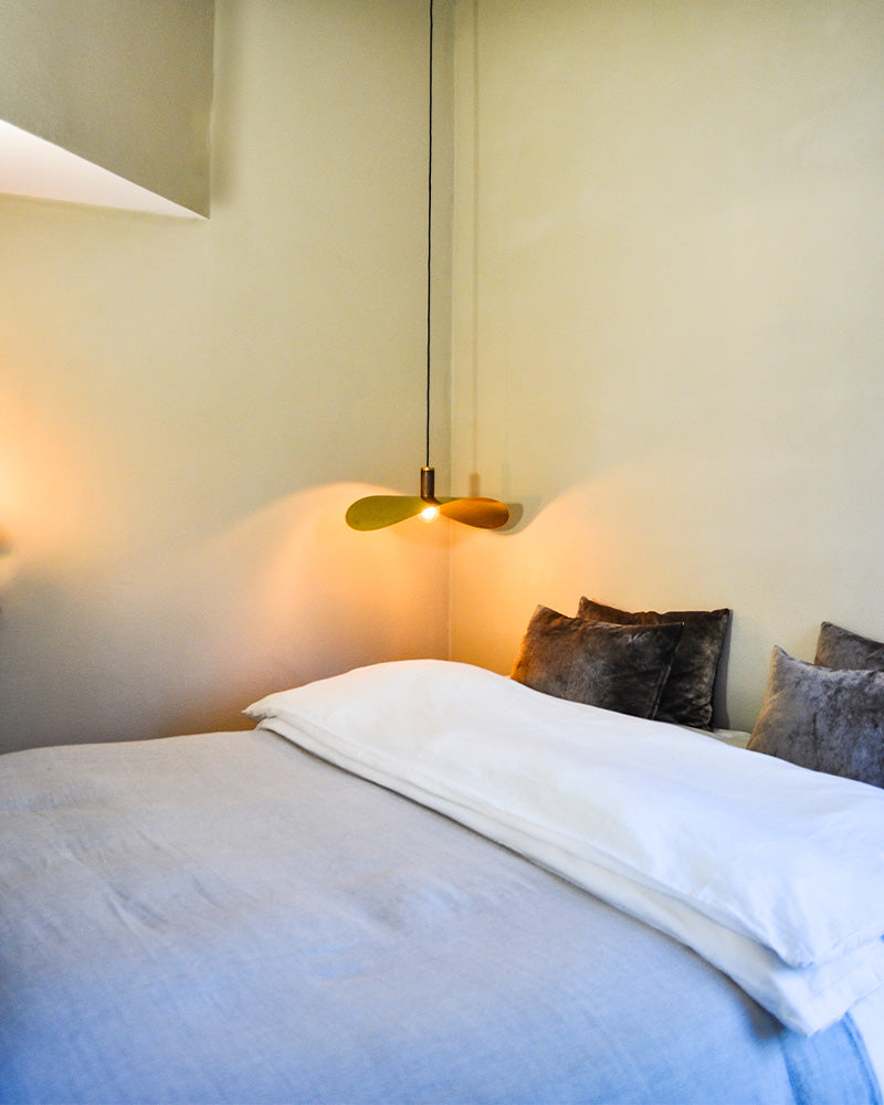 brass pendant light hanging beside a bed