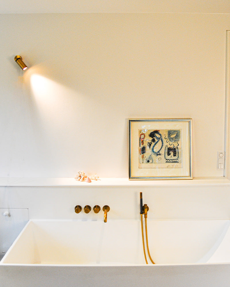 brass spotlight on wall in bathroom with bathtub